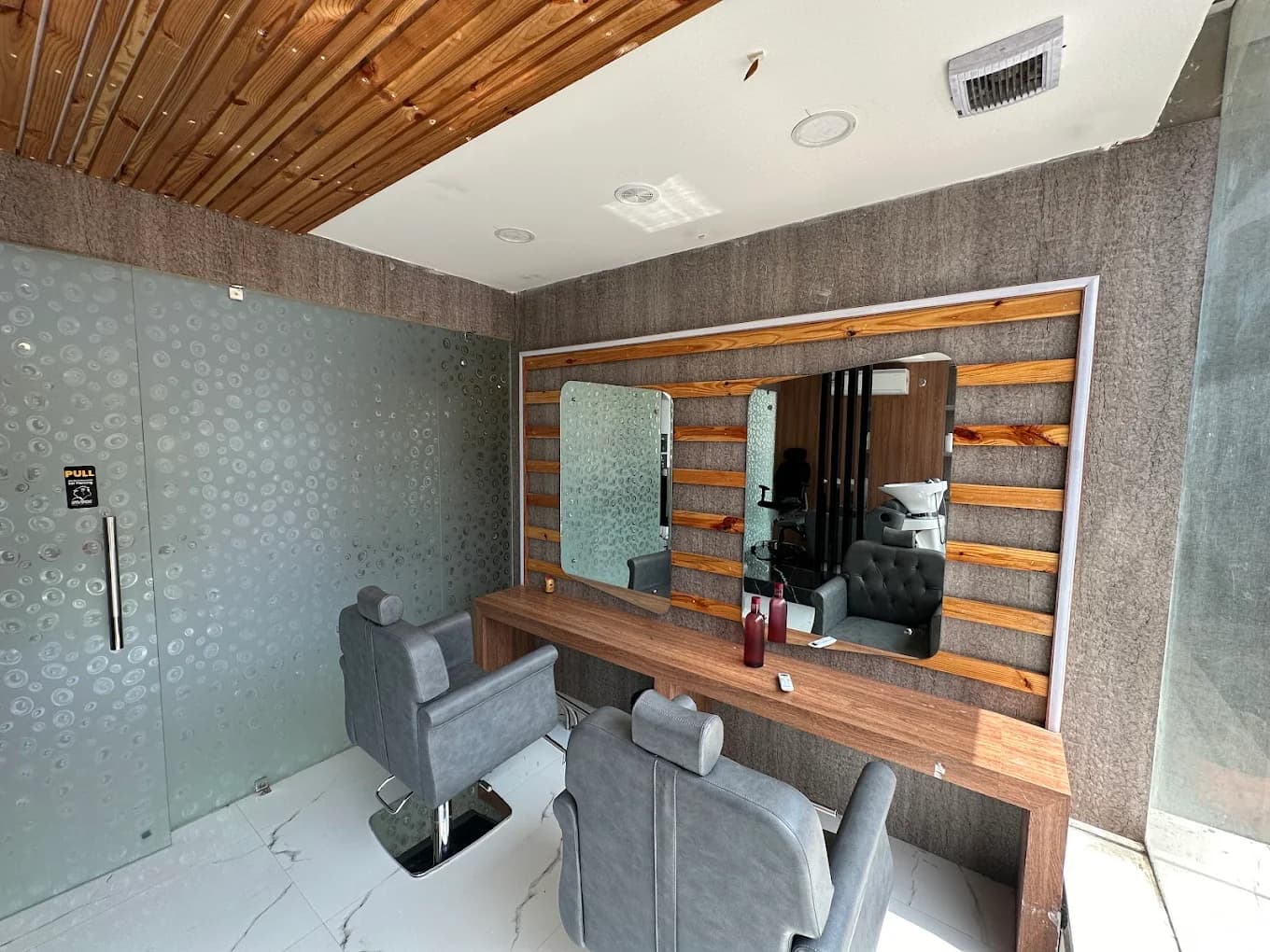 Malkajgiri salon: styling station with textured wood-and-glass wall