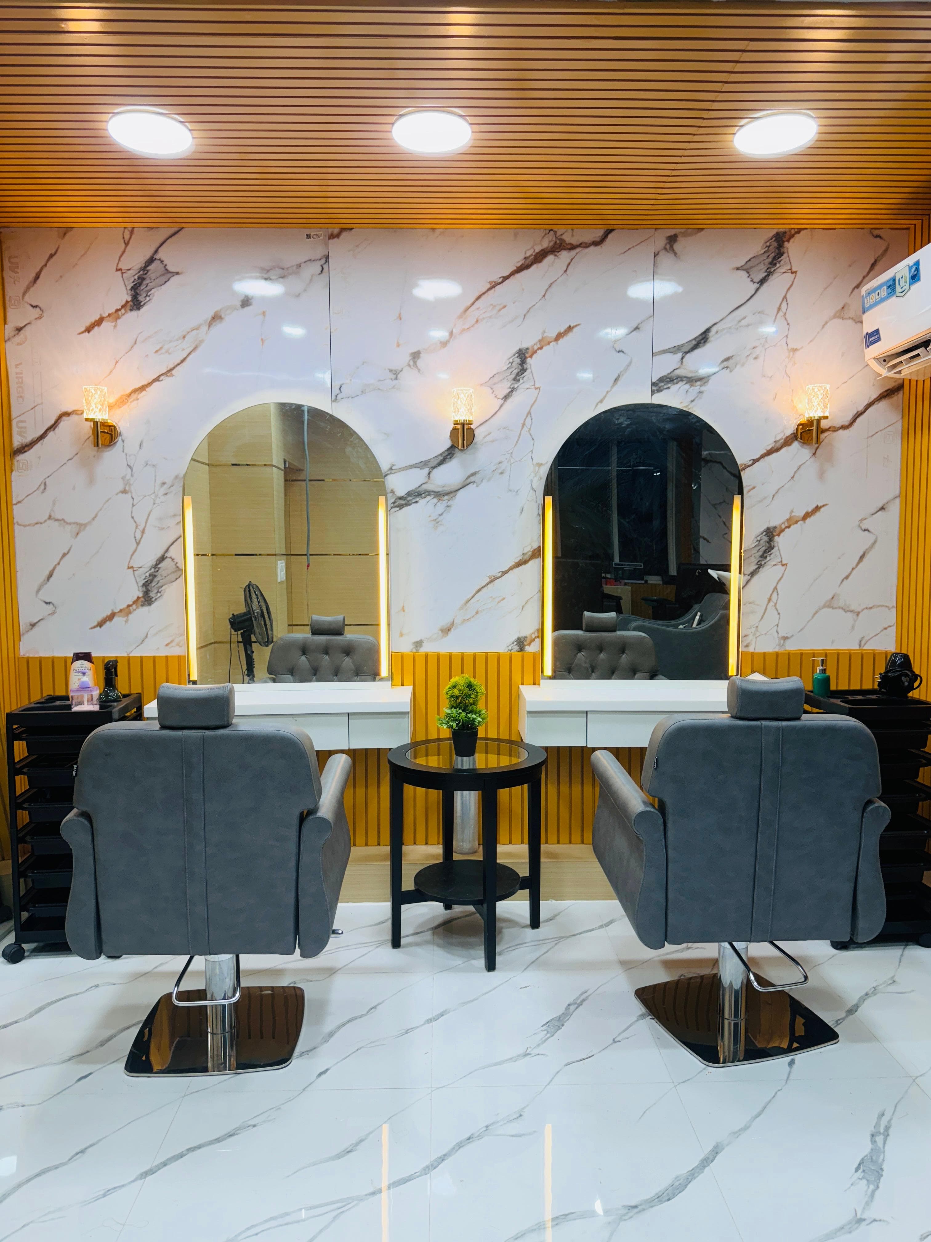 Sainikpuri salon: back view of two styling chairs facing marble mirror wall
